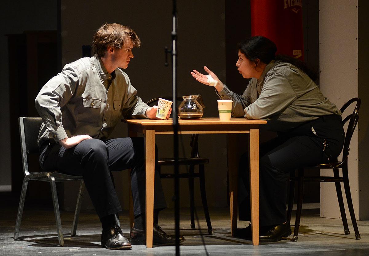 Two students perform a conversation over coffee on stage.
