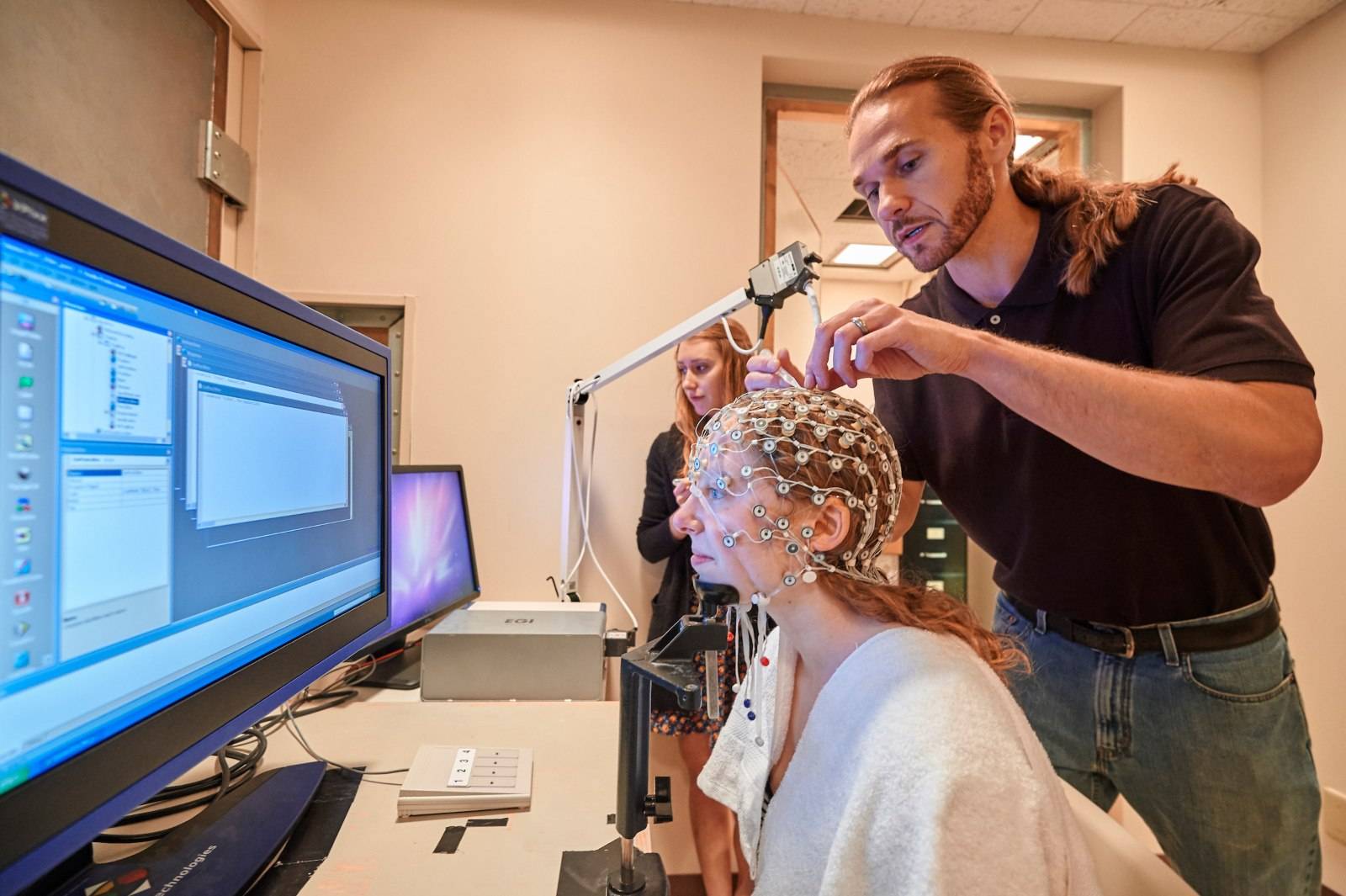 Professor Bruce Hansen places a research set device over a students head